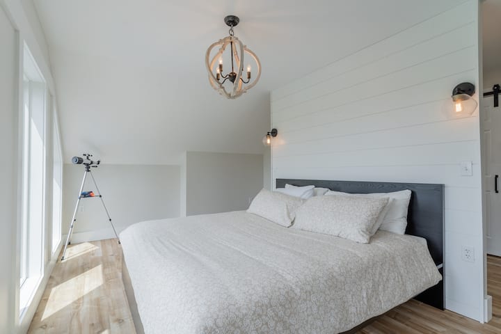 חדר שינה עם מיטת קווין סייז ואפשר ליהנות מנוף למפרץ ומהנהר מחדר השינה