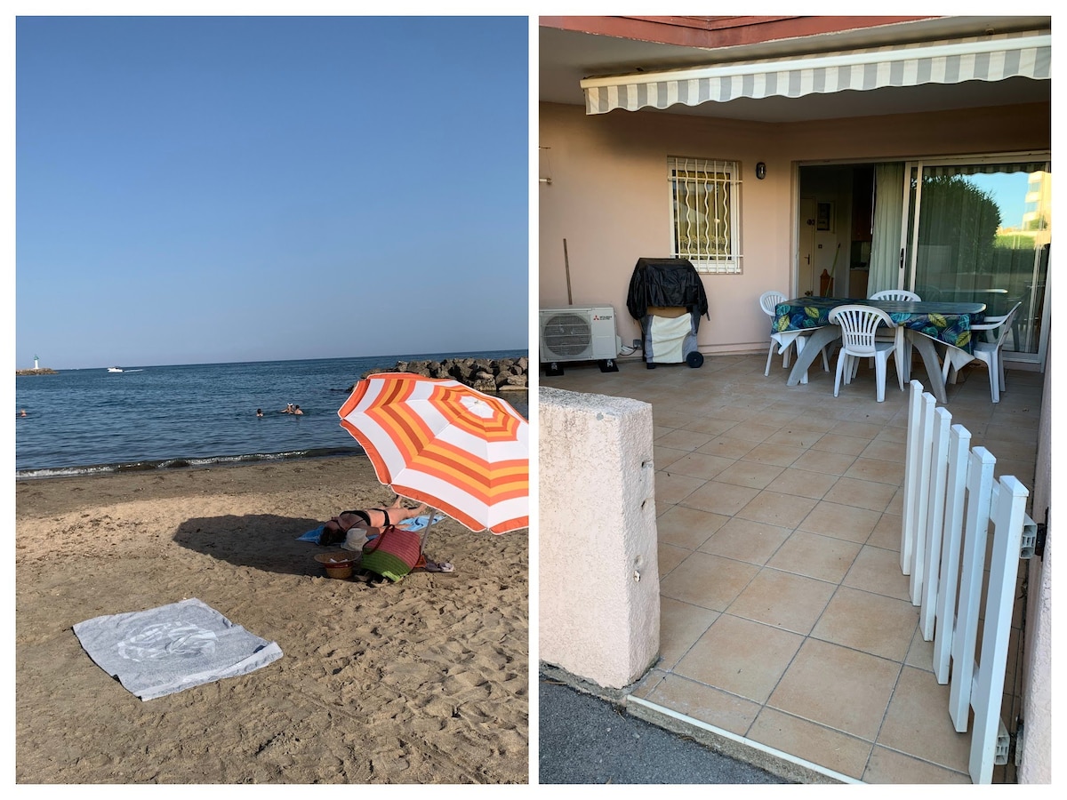 An inviting beachfront scene features a sandy area with a striped umbrella providing shade over a towel. Gentle waves are visible in the distance, while the other side shows a tiled patio with several white chairs and a table, accessible from the nearby accommodation.