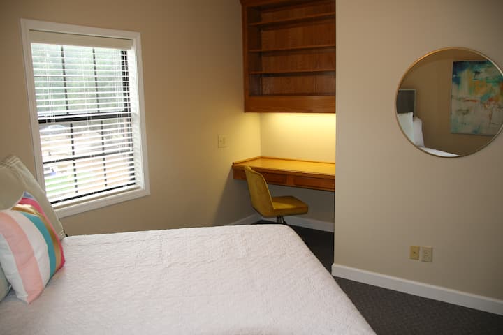 غرفة نوم كبيرة في الطابق العلوي، مع مكتب/منطقة ملابس وكرسي مكتب غير تقليدي.