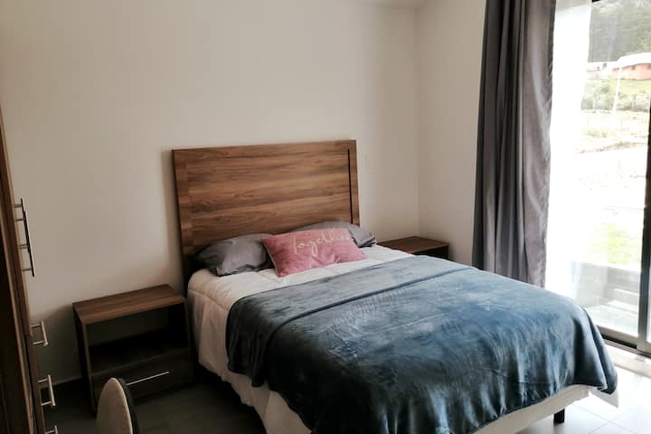 Chumba cha juu kilicho na kitanda cha watu wawili, roshani na dawati lililounganishwa kwenye kabati.