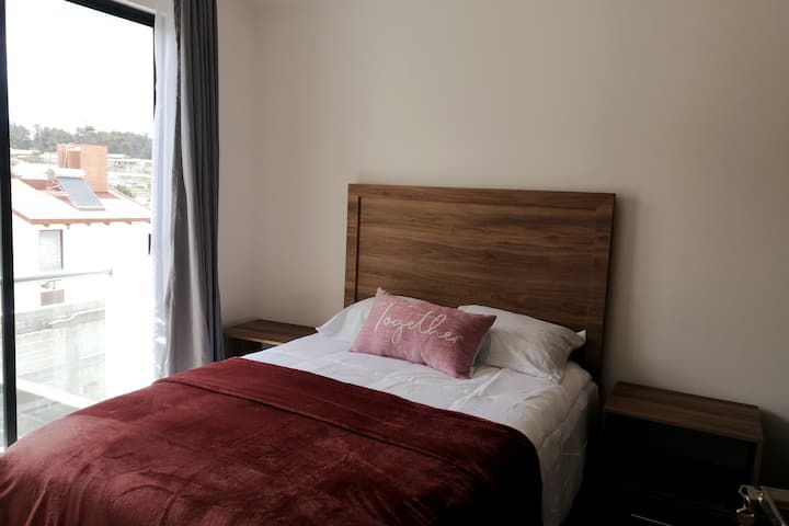 Chumba kilicho na kitanda cha watu wawili ghorofani na dawati lililojengwa kwenye kabati la ofisi ya nyumbani.