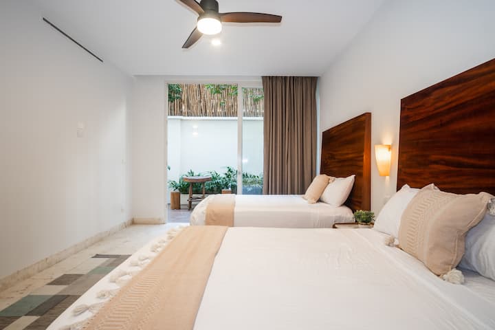 Táto priestranná spálňa má dve pohodlné manželské postele, vlastnú kúpeľňu a priamy prístup na pokojnú záhradnú terasu - ideálna pre rodiny alebo priateľov, ktorí cestujú spoločne.