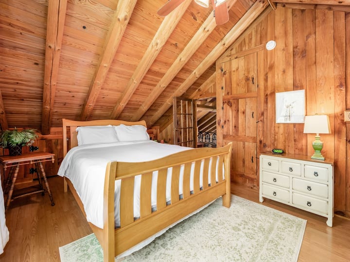 Cuenta con un cómodo dormitorio con paredes y techo de paneles de madera, una lujosa cama tamaño queen y una encantadora estética rústica. Perfecta para una escapada relajante, esta habitación ofrece un ambiente sereno y una conexión con la naturaleza.