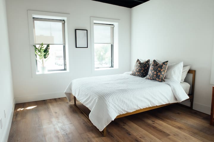 爽やかな寝具と穏やかな自然光が、快適な滞在をお約束する、風通しの良いミニマルなクイーンベッドルーム。