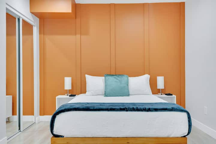 Bedroom 3: Queen-size bed and closet space. Modern design with orange accent wall.