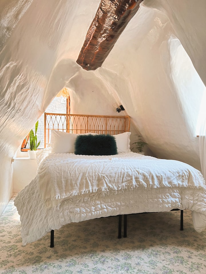 Tu acogedora suite principal con una cama tamaño queen, cama firme y sábanas de 100% algodón está ubicada en el espacio loft semi abierto sobre el rincón de la cocina. 