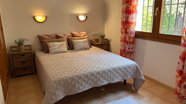 تتميز غرفة النوم الجذابة هذه بسرير مزدوج مريح تحيط به طاولتان بجانب السرير، تحتوي كل منهما على مصباح للإضاءة المحيطة. تسمح نافذة كبيرة بدخول الضوء الطبيعي، مما يخلق جوًا هادئًا وممتعًا