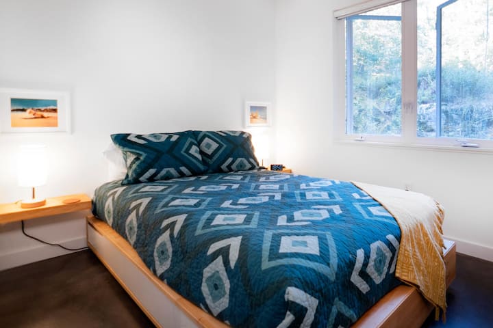 Bedroom #2 has a full sized mattress on a platform storage bed with drawers, a ceiling fan, a closet, and floating shelves for phone charging.  Additionally, there is an Amazon Echo Dot with access to unlimited music.