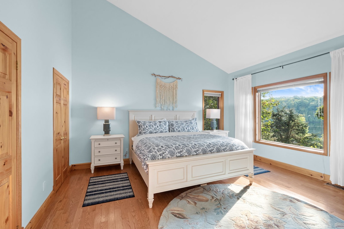 Dormitorio principal con una enorme cama tamaño king, vistas al lago y baño privado en el nivel superior.