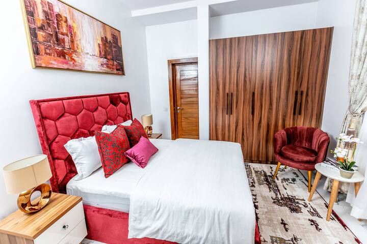 Une chambre charmante avec un très grand lit, une literie confortable et des lampes de chevet élégantes. La lumière naturelle filtre à travers les rideaux doux, mettant en valeur le décor de bon goût et créant un espace serein et reposant pour les voyageurs.