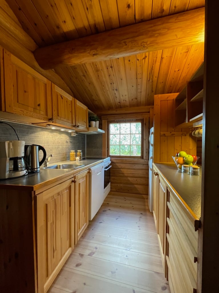 The kitchen features wooden cabinetry and countertops, providing a warm and rustic feel. A window allows natural light to enter, illuminating the space. Included are essential appliances, such as a coffee maker and refrigerator, ensuring convenience for guests.