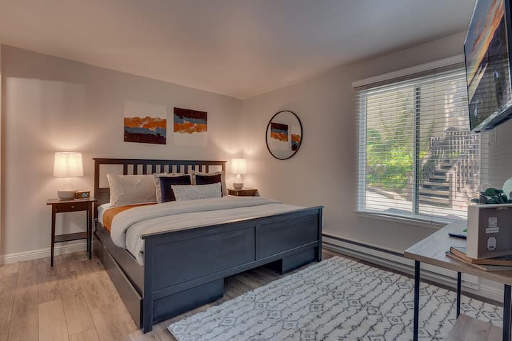 Unwind in the spacious master suite featuring a plush king bed, private ensuite bathroom, smart TV, and ample natural light from the large picture window — the perfect retreat after a day of Lake Tahoe adventure.