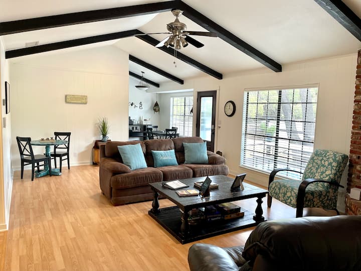 Това светло жилищно пространство с отворена концепция разполага със сводести тавани с видими греди, удобни места за сядане и големи прозорци с изглед към дърветата. С игри, уютни кътчета и кът за хранене, то е създадено за общуване и отдих.