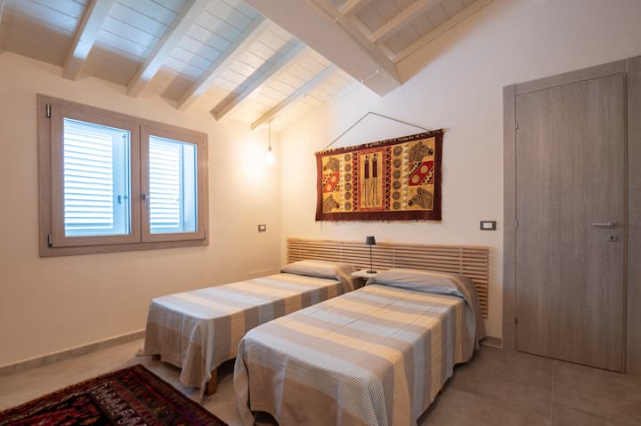 חדר שינה עם שני כיסאות שיזוף שניתן להפוך למיטה זוגית