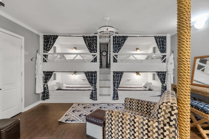 Queen's Gambit. Four queen over queen, side by side bunk beds with privacy curtains. Each bed has its own dimable light, an outlet with a shelf above to rest a charging phone,  and a built-in niche shelf to safely rest a drink, book or game console. 