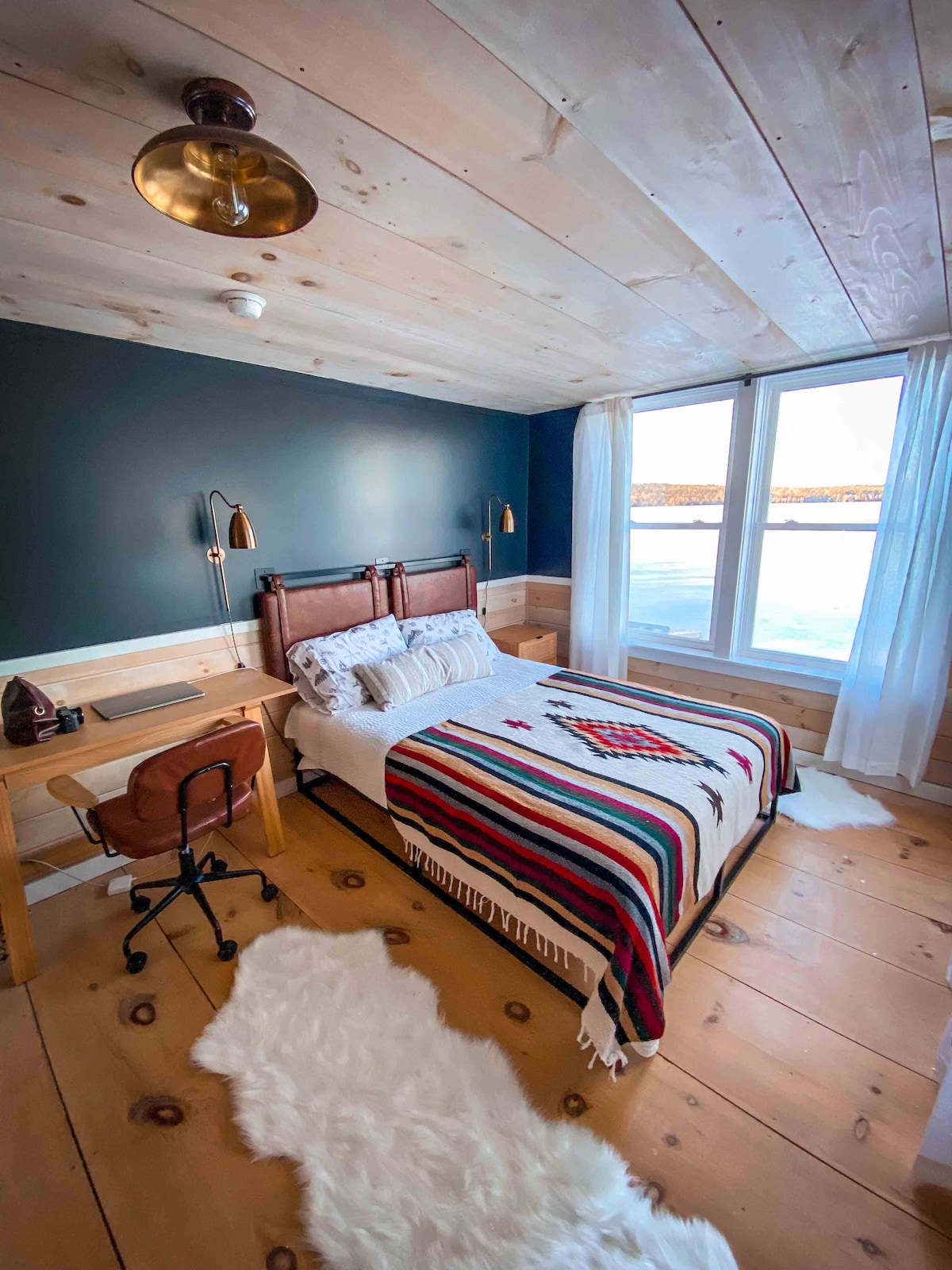 This bedroom features a queen bed, waterfront views, a designated work area and a closet. 