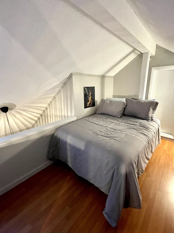 Лофт с пълноразмерно легло, разположено над кухня/трапезария/всекидневна.