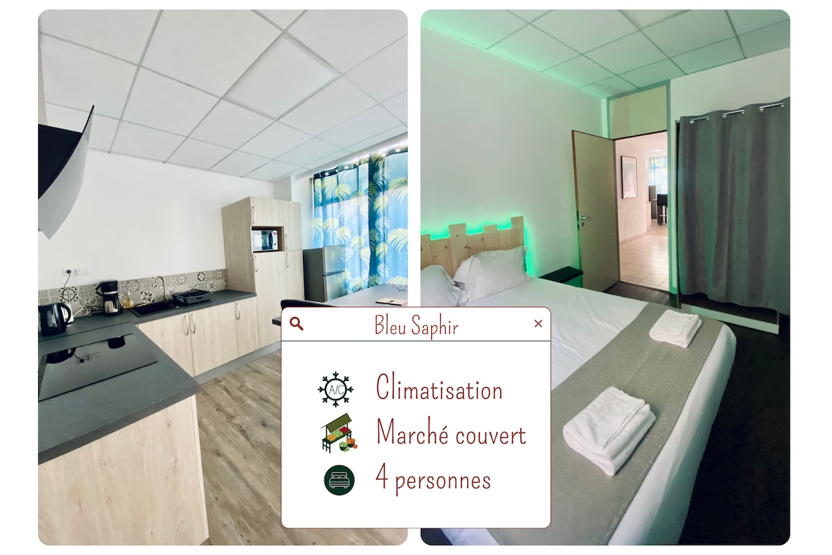 The image shows a well-lit apartment featuring a modern kitchen with essential appliances and an open layout. A spacious sleeping area with a comfortable bed is visible, highlighted by ambient lighting. A dividing curtain indicates a separate living space, contributing to the overall functionality.