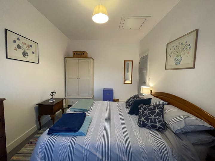 Dormitorio 1 - segundo ángulo. Cama tamaño king, armario, cómoda y silla junto a la cama con vistas al pueblo al campo circundante.
