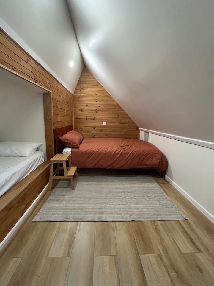 Large attic (4th bedroom) with 1 queen bed and 2 king single beds (in nooks). Accessible via steep stair and available for larger group bookings only. 