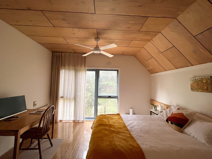 Second bedroom (queen bed) with large windows and a study desk