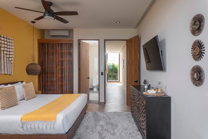 Habitación moderna con cama tamaño king. Cuenta con hermosas decoraciones, un baño, TV, un ventilador de techo y aire acondicionado.