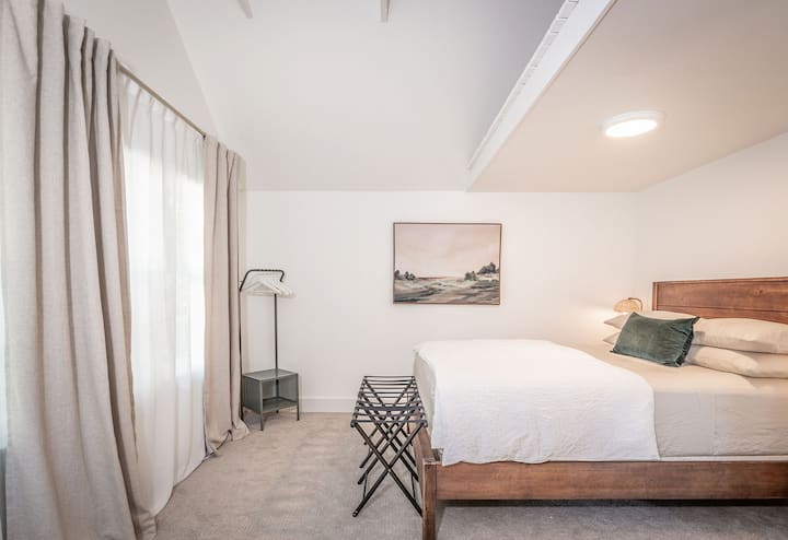 El dormitorio de la planta principal cuenta con una cama tamaño «queen», portaequipajes y un sillón.