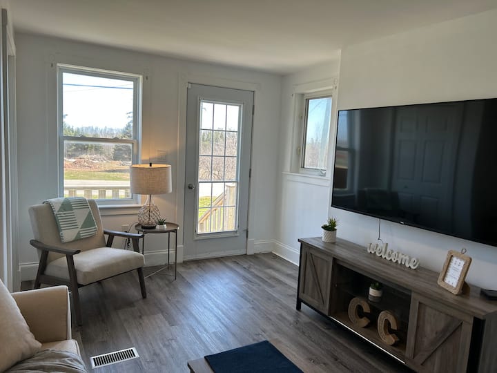 Relax in comfort in our spacious living room, complete with a cozy pull-out couch, 65-inch smart TV, and plenty of natural light streaming in from the windows.