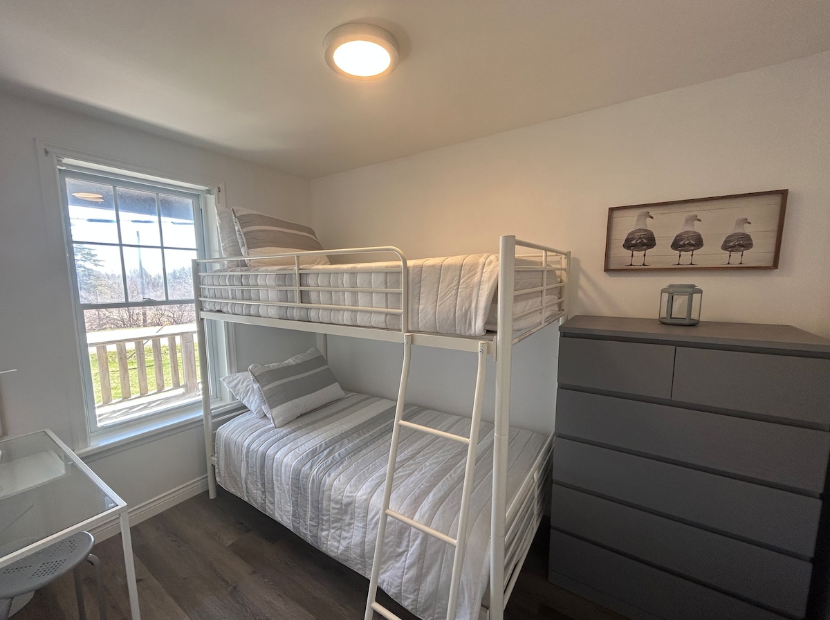 A cozy and functional space for two guests, our bunk room features a sturdy bunk bed, a spacious closet, a convenient desk and workspace, a dresser, and a bright window that lets in natural light.