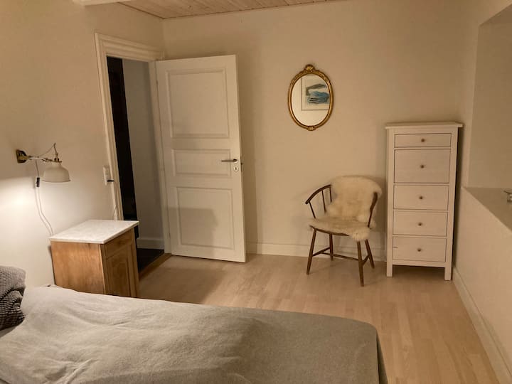 Værelse 1: dobbeltseng bestående af 2 enkeltsenge sat sammen. Kommode til tøj og knager bag døren.