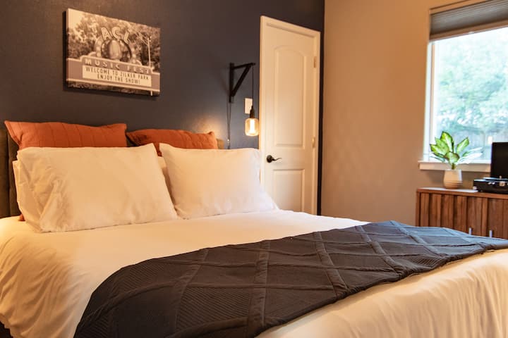 This bedroom has one queen bed with a walk-in closet, and a workspace. It's connected to shared bathroom with a shower/tub combo.