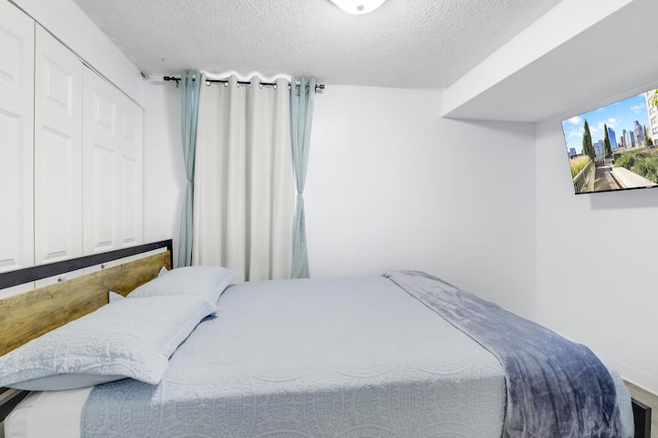 Cozy bedroom with a plush queen-sized bed and a wall-mounted TV for ultimate relaxation.
