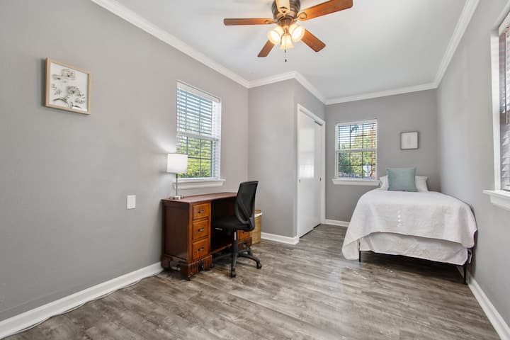 Dormitorio trasero con vistas al patio delantero, a la entrada y al patio trasero vallado; incluye un escritorio para trabajar y un televisor inteligente de alta definición (Roku).