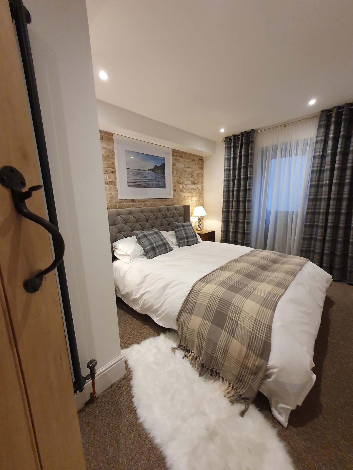 Slaapkamer 2 heeft een kingsize bed, meubels in industriële stijl en toegang tot een functionele binnenplaats en een poort naar het achterpad rond de kerk.