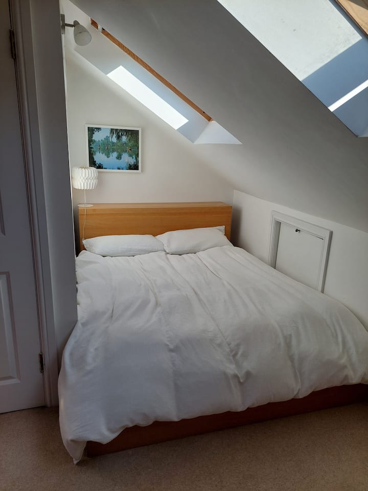 ห้องนอนใต้หลังคาพร้อมเตียงคิงไซส์และพื้นที่ทำงาน