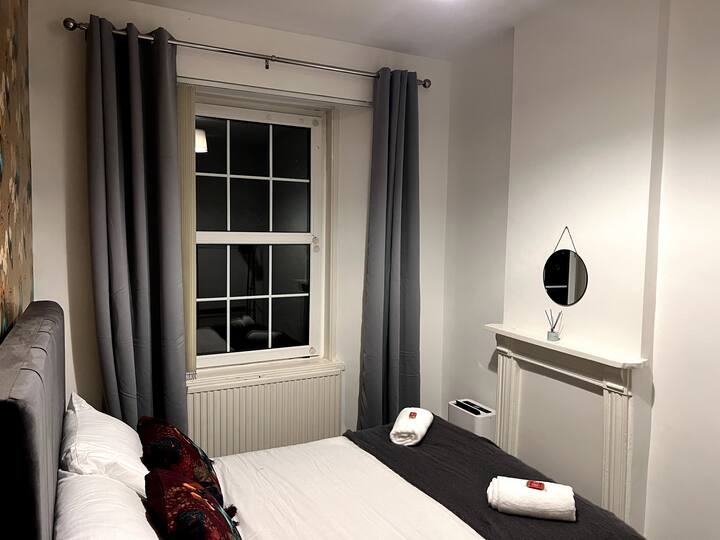 Træd ind i soveværelse 2 med en kingsize-dobbeltseng, frisk sengetøj, rene håndklæder, en tøjbøjle, et spejl og moderne vægdesign til et stilfuldt og behageligt ophold.