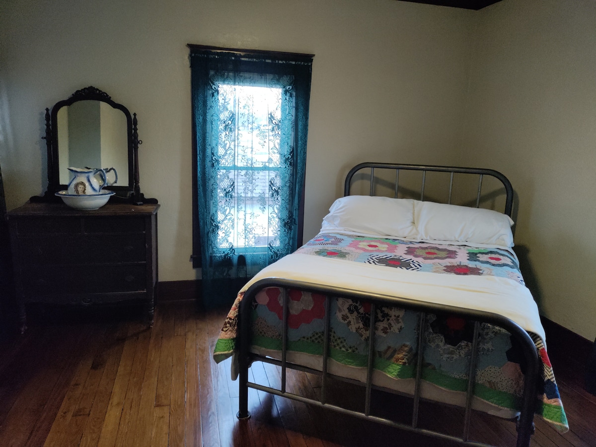 ห้องนอน NW มีเตียงโลหะสไตล์วินเทจขนาดใหญ่และตู้เสื้อผ้าโบราณพร้อมเหยือกซักผ้าและชาม