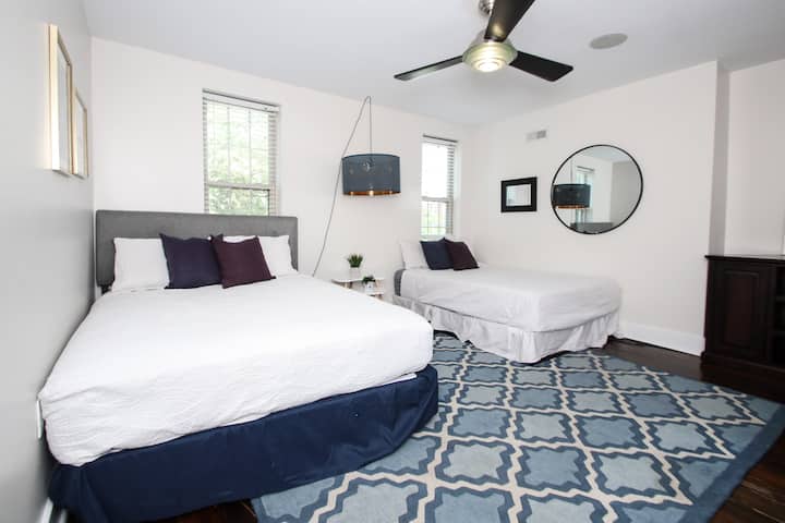 חדר שינה מרווח עם שתי מיטות נוחות, עיצוב מסוגנן ואור טבעי.