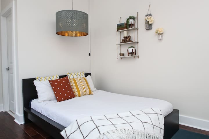 סביבה שלווה עם מדפים דקורטיביים, כריות רכות ואור תליון מודרני למגע מסוגנן.