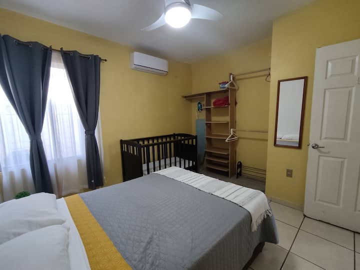 Recámara matrimonial equipada con aire acondicionado, plancha, burro para planchar, closet con ganchos,  espejo, cuna y cortinas blackout para evitar la luz del día. Con conexión al baño.