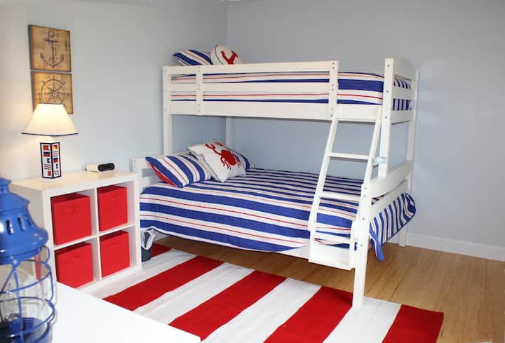 Habitación litera con colchón completo (en la parte inferior) y dos camas individuales (en la parte superior). Reloj de noche con conexiones de alimentación y USB para alimentar tus dispositivos.