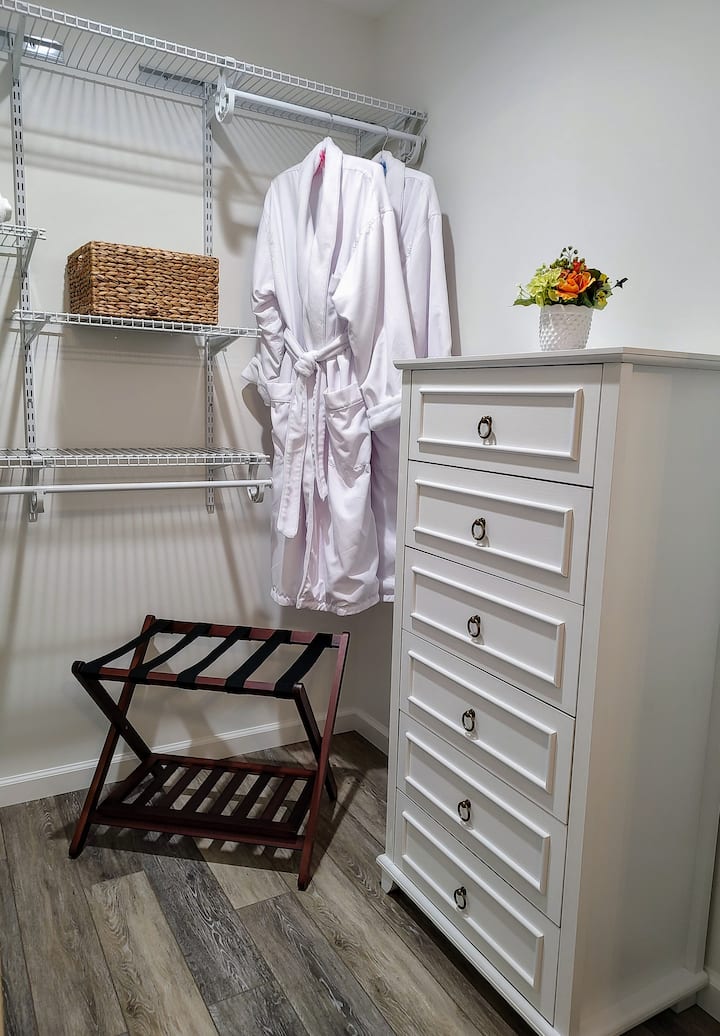 Spacious walk-in closet with cozy  robes, dresser & luggage rack