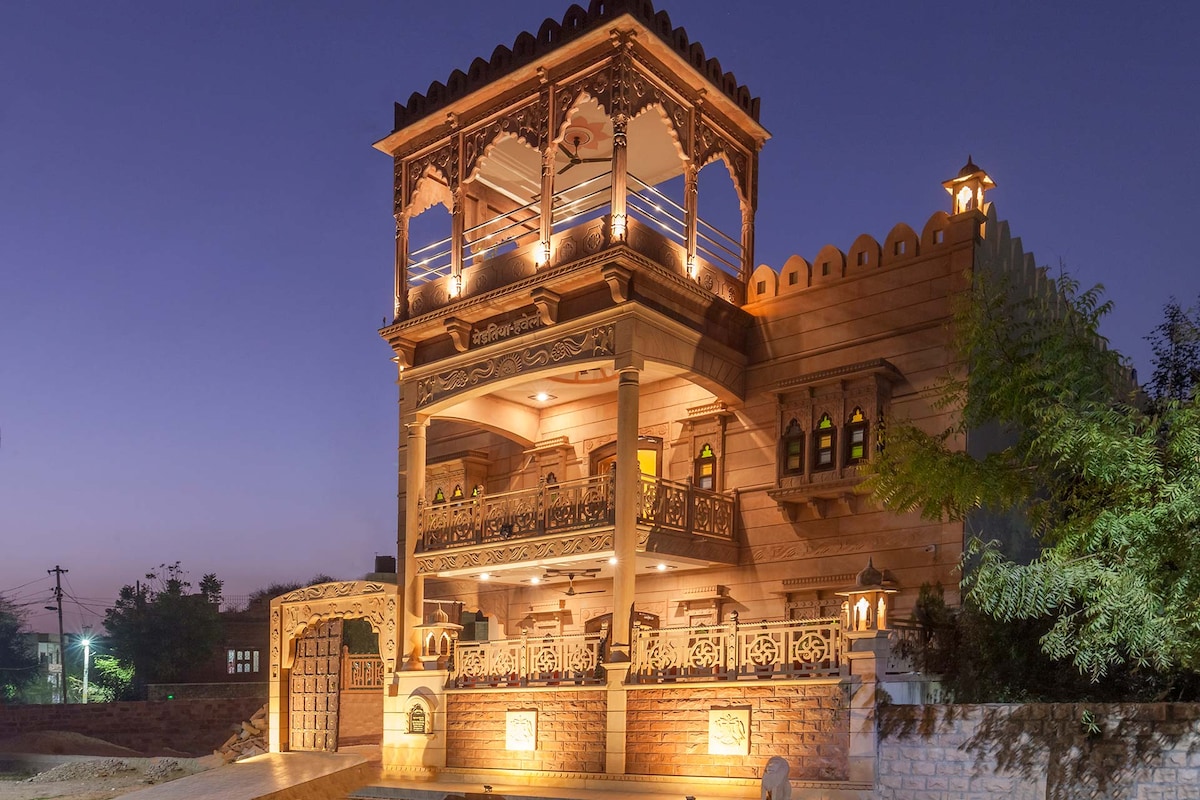 The heritage home stands elegantly, showcasing intricate architectural details under a twilight sky. Illuminated by warm lights, the structure features ornate balconies and traditional carvings, while the inviting entrance highlights its unique design.
