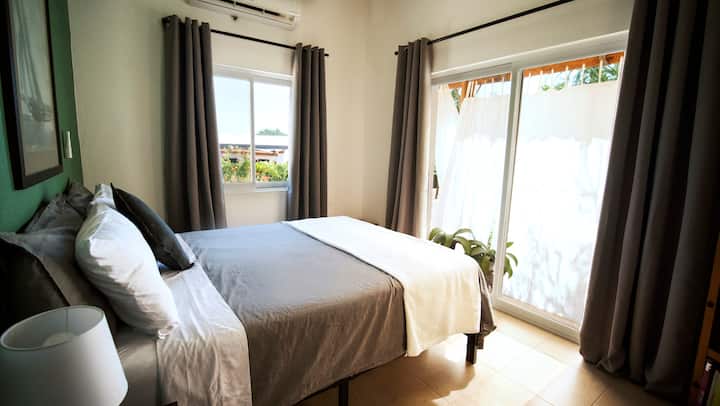 Dhomë gjumi kryesore me dyshek me shkumë memorie dopio "queen" dhe perde të errëta 