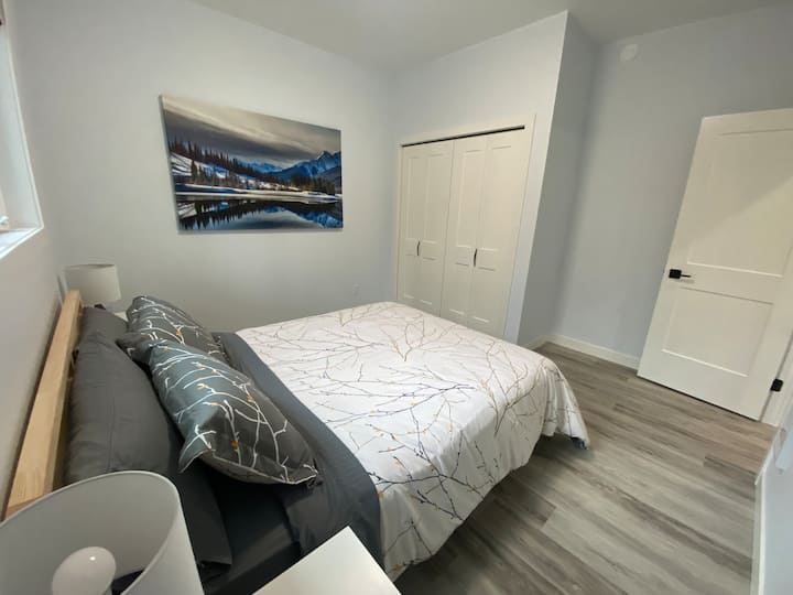 Chumba kikuu cha kulala chenye kabati kubwa lenye sehemu ya hanger na kabati la kujipambia. Kitanda cha malkia kilicho na luva zilizozimwa. 