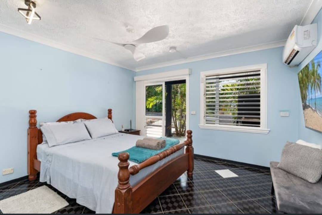 Chumba cha kulala cha ghorofa ya chini kilicho na kitanda aina ya queen na televisheni, A/C na feni ya dari.