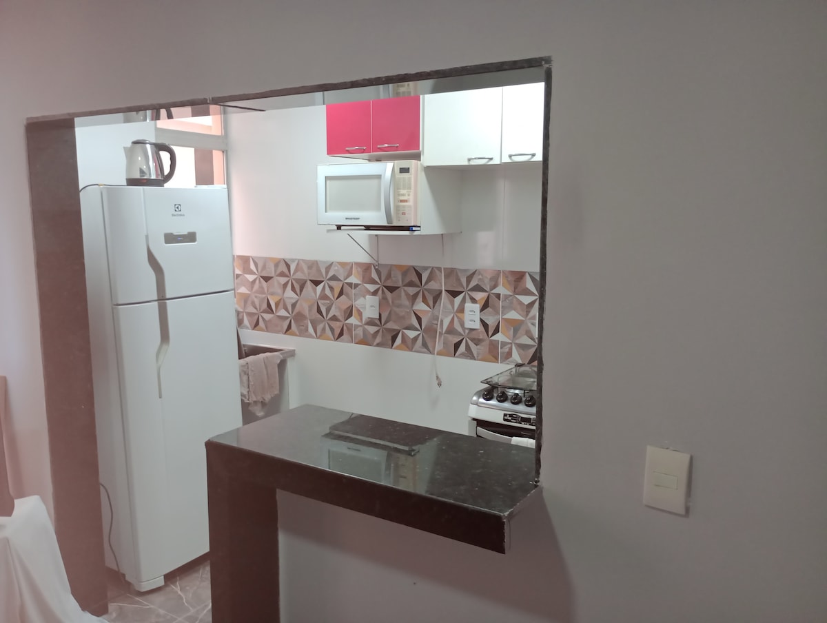 A thorough view of a kitchen area is presented, featuring a modern refrigerator, microwave, and stove arranged against a patterned backsplash. A bar counter provides a transition between the kitchen and living space, enhancing the open layout. The kitchen cabinetry offers a blend of colors.