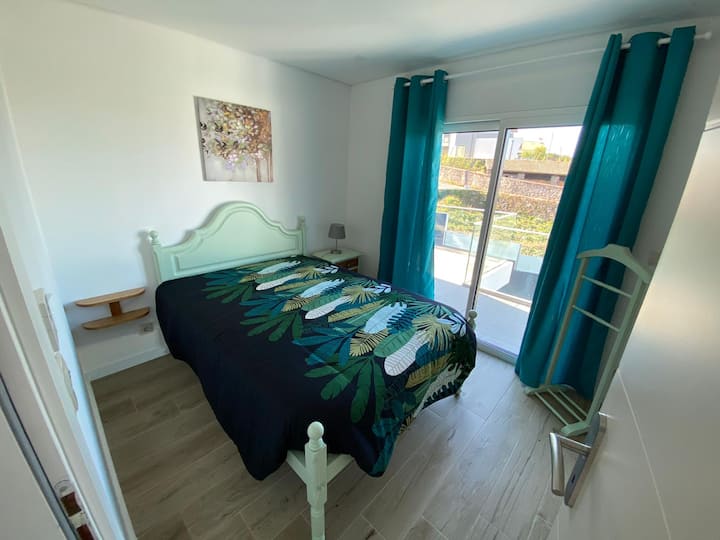 Chambre de couple avec accès au patio, volets occultants et armoire intégrée avec beaucoup de rangement.