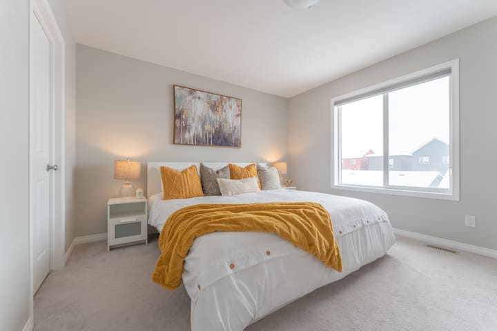 Dormitorio principal con una cama tamaño king y una gran ventana para permitir mucha luz solar.