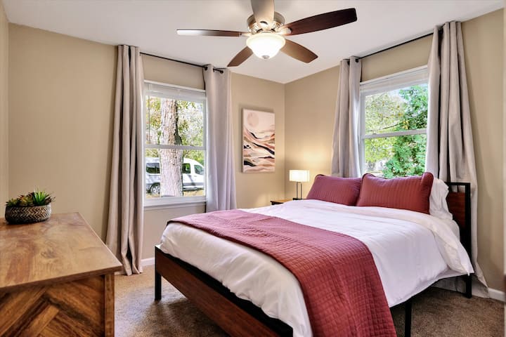 غرفة نوم تضم سرير كوين مع ستائر مظلمة 